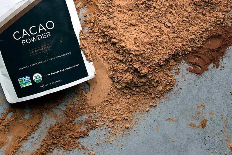 A bag of raw cacao powder on top of the cacao powder itself.