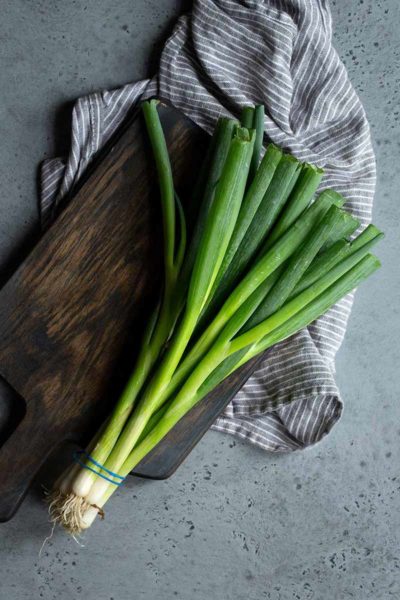 bunch of scallions on a cutting board with a napkin