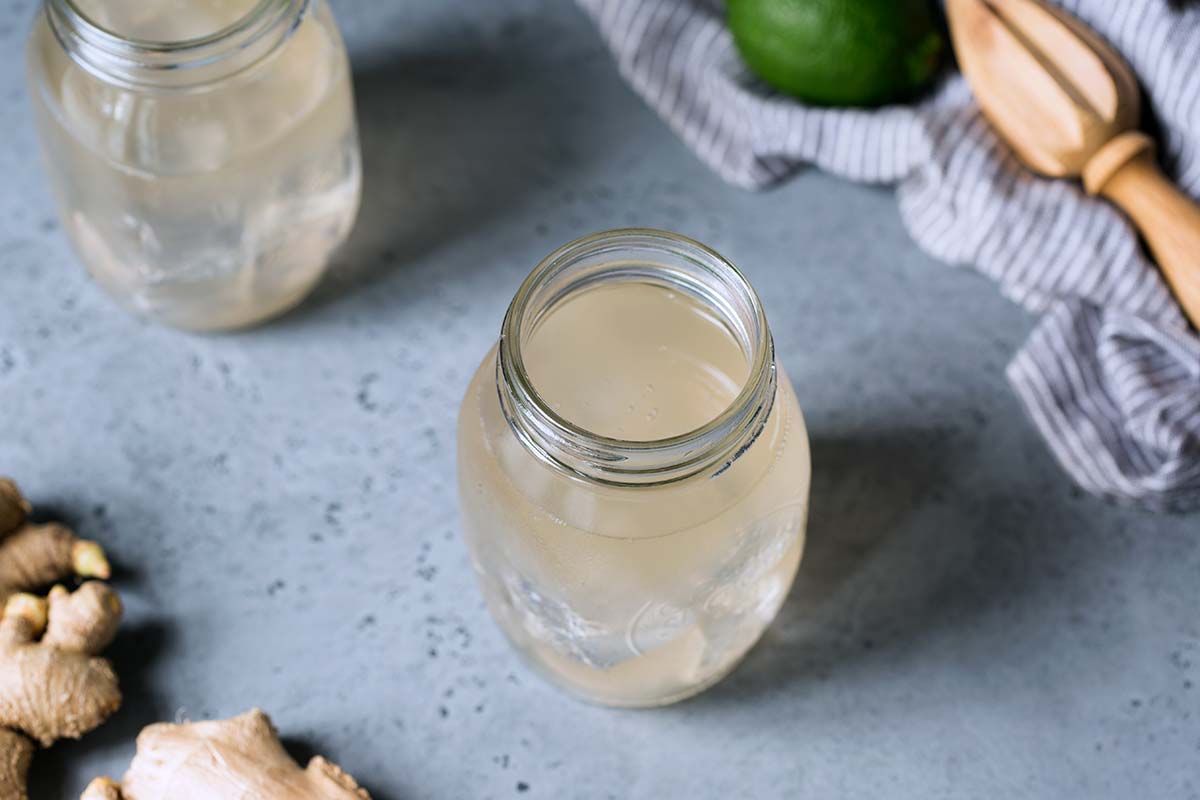 Homemade ginger ale recipe surrounded by fresh ginger and lime.