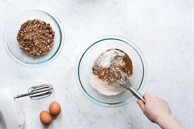 Dry ingredients for pumpkin muffin recipe in a bowl, being mixed with a whisk