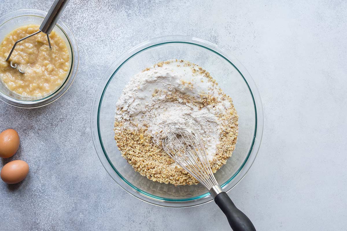 Ingredients for banana nut bread in a bowl with a whisk.