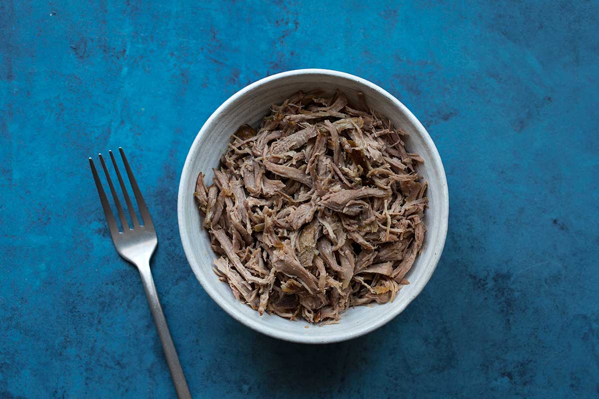 Slow cooker pulled pork in a bowl with a fork
