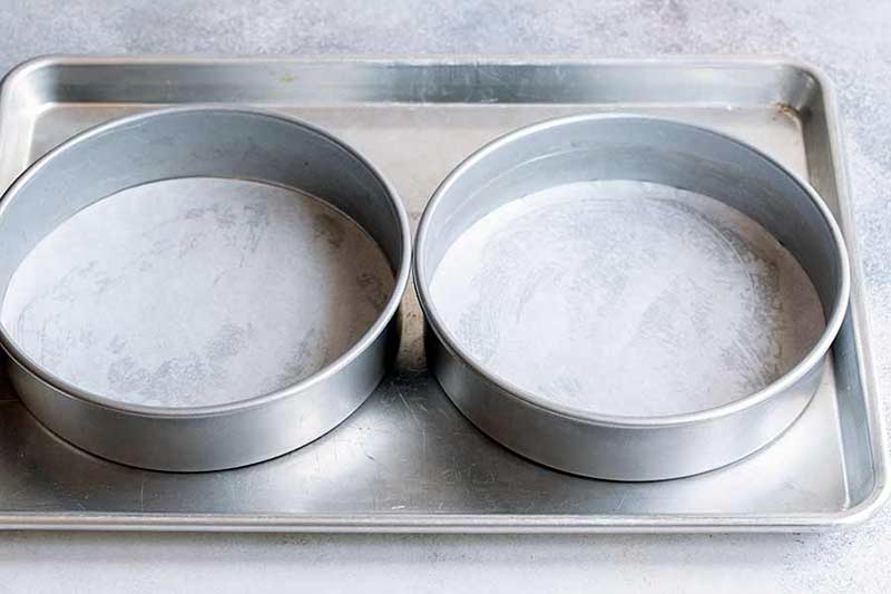 two greased cake pans on metal baking sheet