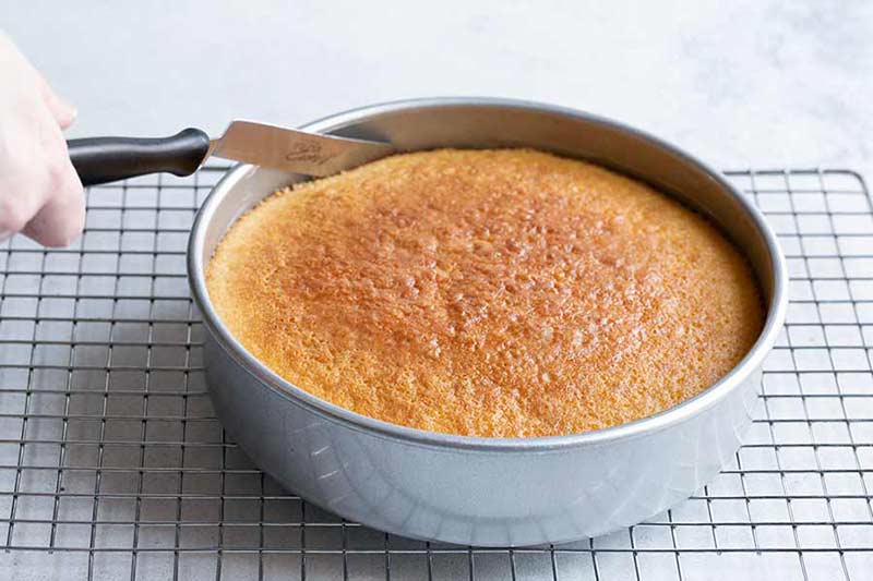 running an offset spatula around the edge of a baked yellow cake