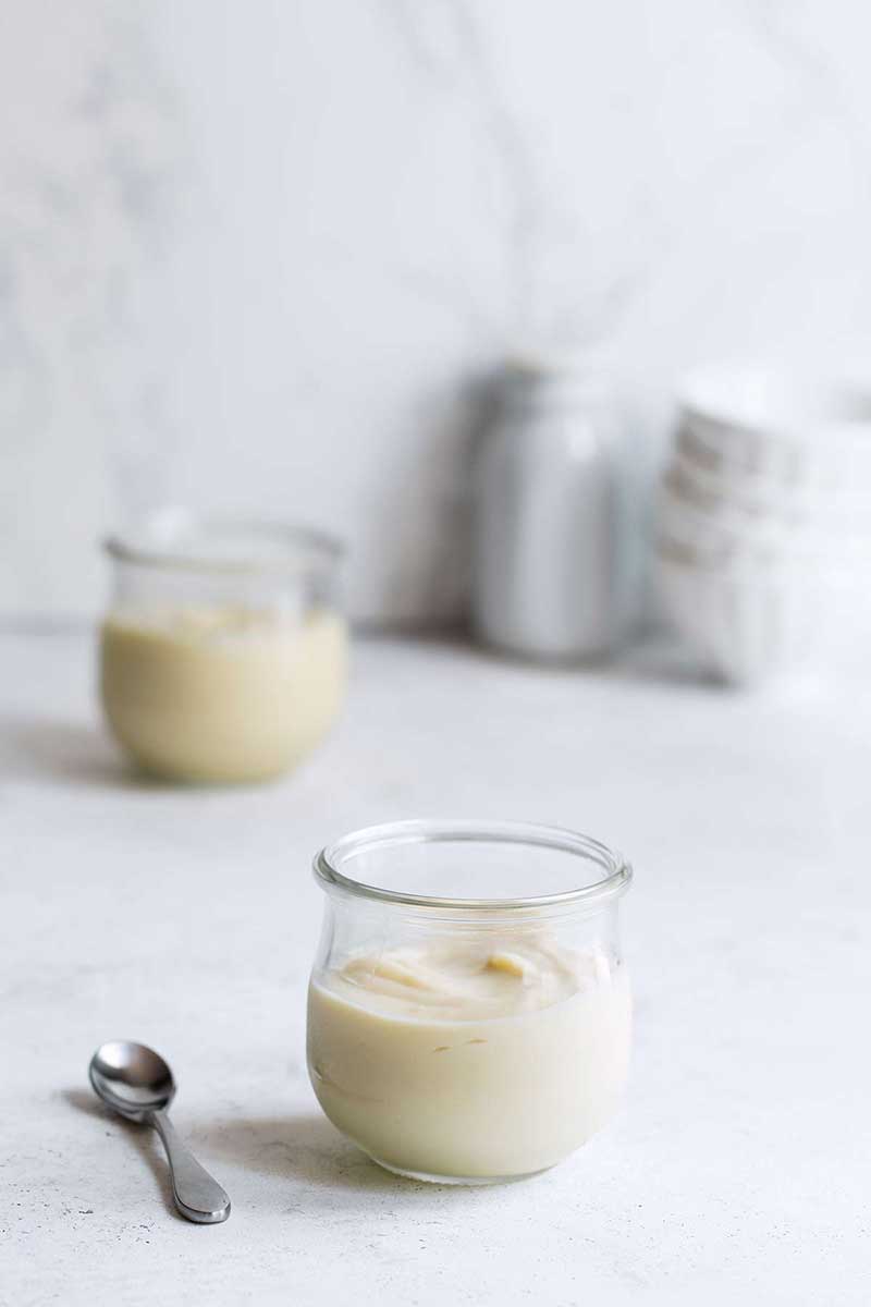 Vanilla pudding recipe in small mason jars on a white backdrop