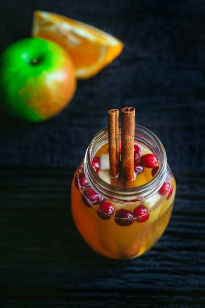 overhead image of fall sangria in mason jar glass with cinnamon sticks and fresh cranberries