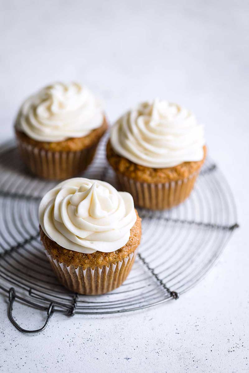 Closeup of three moist carrot cupcakes with cream cheese frosting