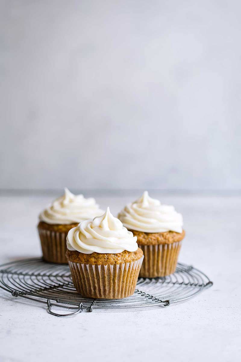 3 frosted cupcakes on a cooling rack