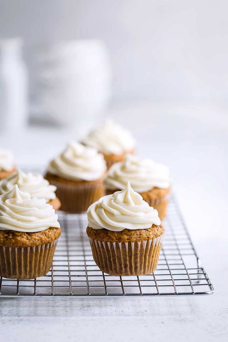 moist carrot cupcakes with cream cheese frosting on a cooling rack