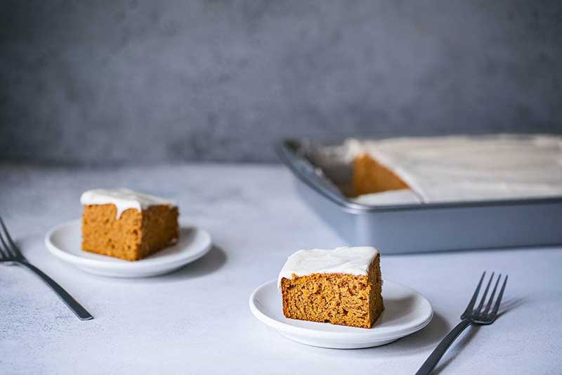 Two slices of pumpkin cake next to the remaining unsliced cake.