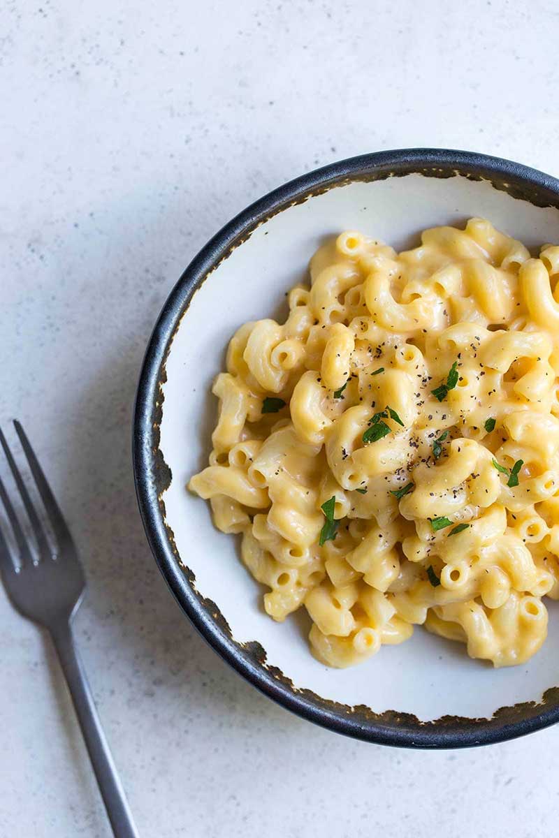 Homemade mac and cheese made from scratch in a bowl with a fork next to it.