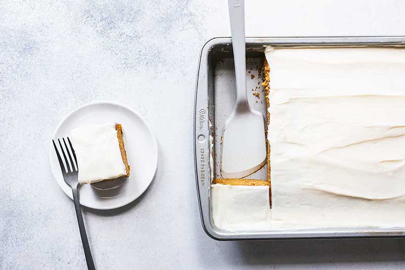 A slice of pumpkin cake next to the pan of cake.