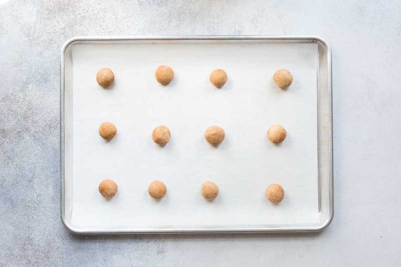 Raw snickerdoodle cookies on a sheet pan, ready to bake.