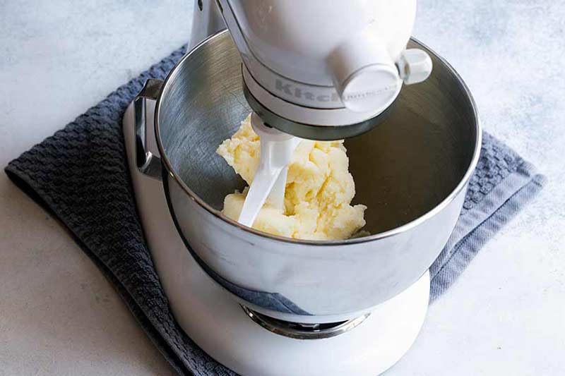 butter and sugar being creamed in bowl of standing mixer