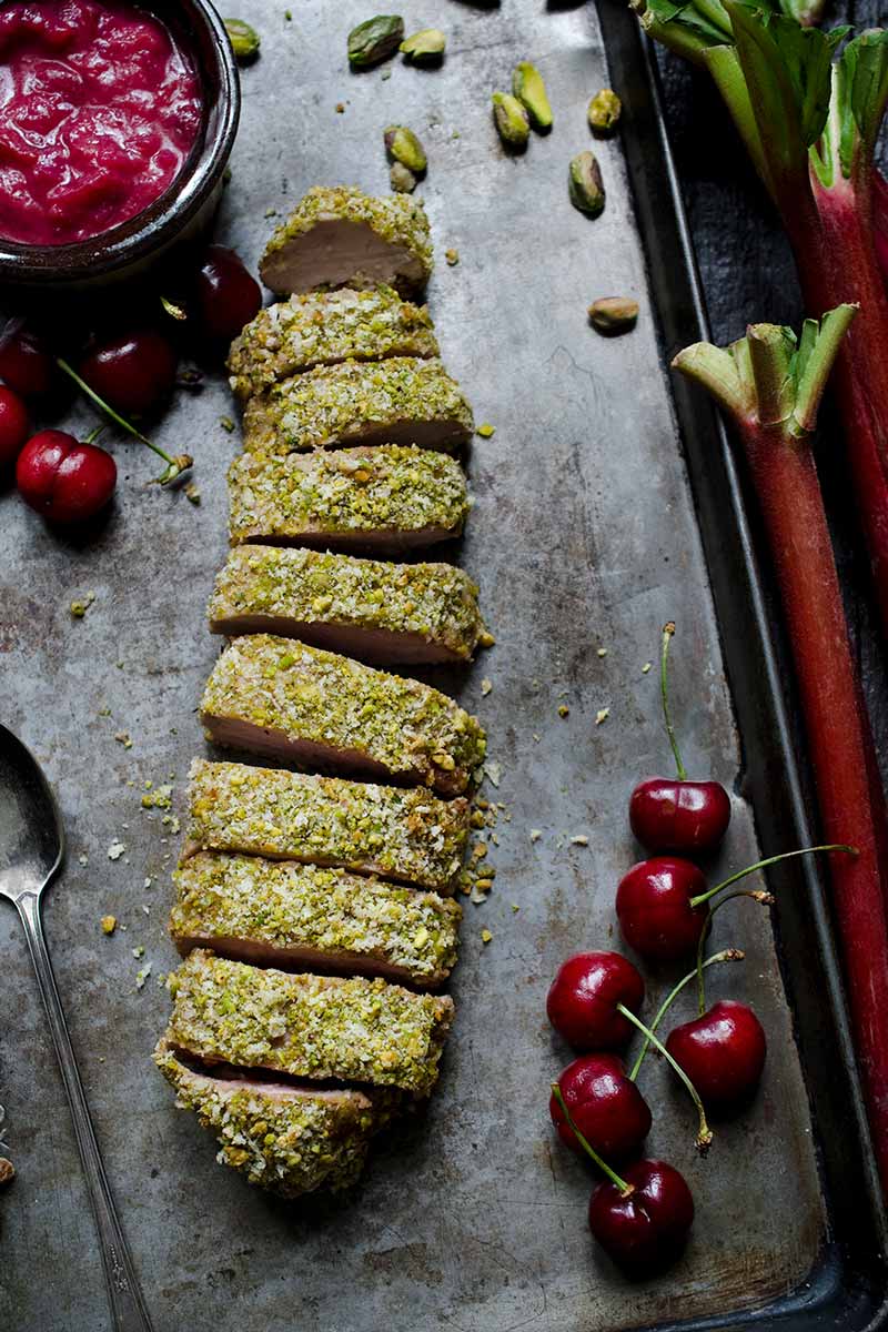Pistachio crusted pork tenderloin surrounded by cherries