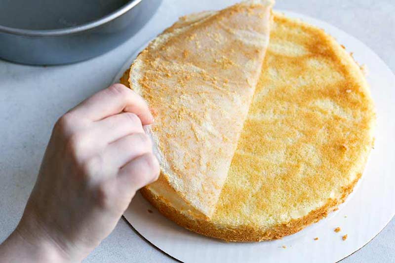 removing parchment paper from the bottom of a yellow cake