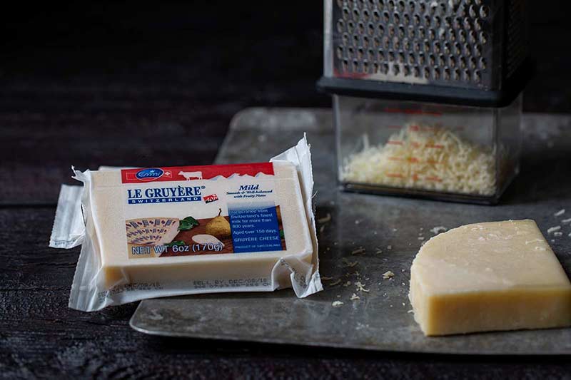 Emmi Gruyere Cheese next to a cheese grater