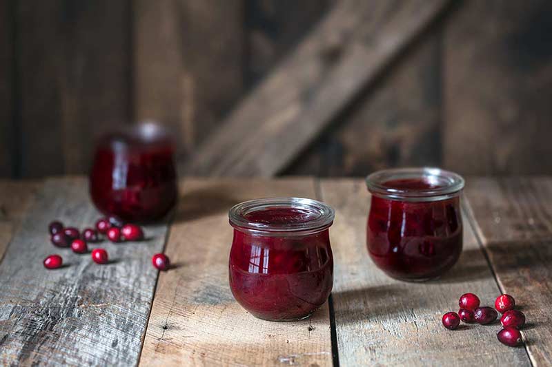 Cranberry orange sauce in mason jars, surrounded by cranberries