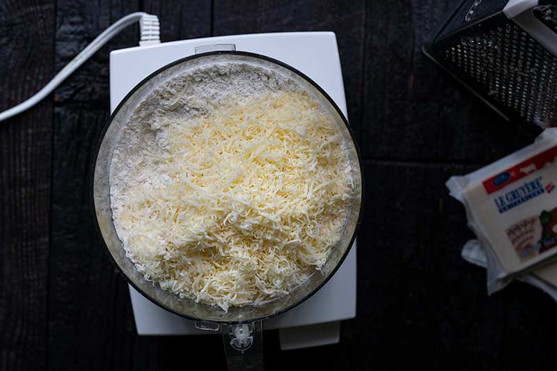 Cheese and pie dough ingredients in a food processor