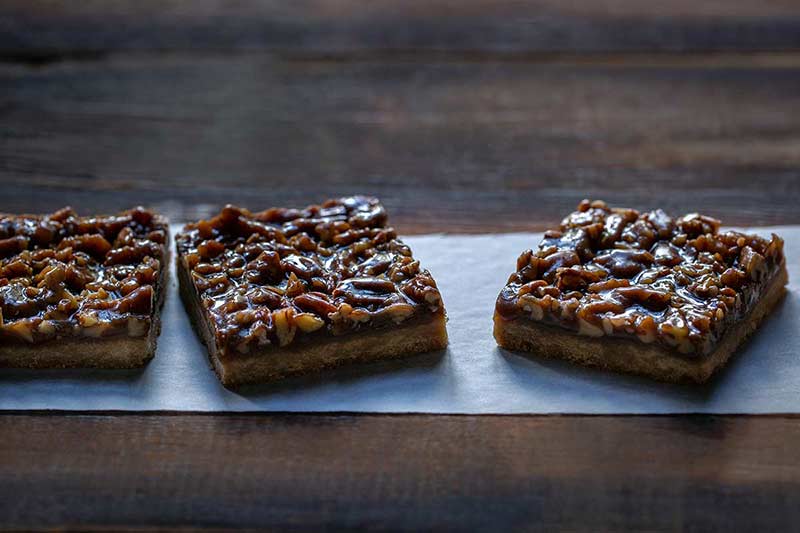 Three pecan pie bar slices on parchment