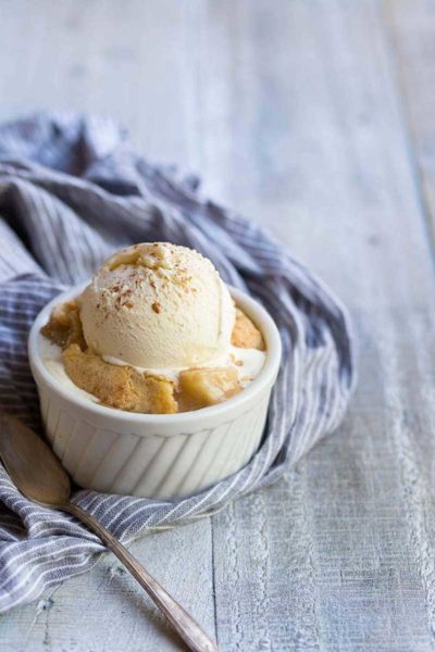 Pear cobbler recipe in a ramekin, topped with ice cream and cinnamon
