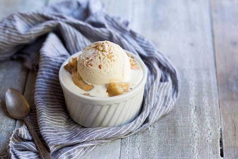Pear cobbler recipe in a ramekin, topped with ice cream and cinnamon