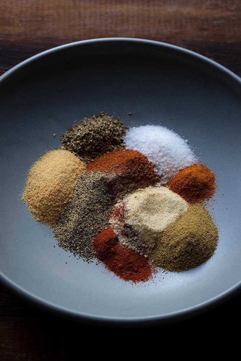 Various spices for taco seasoning spread out on a plate.