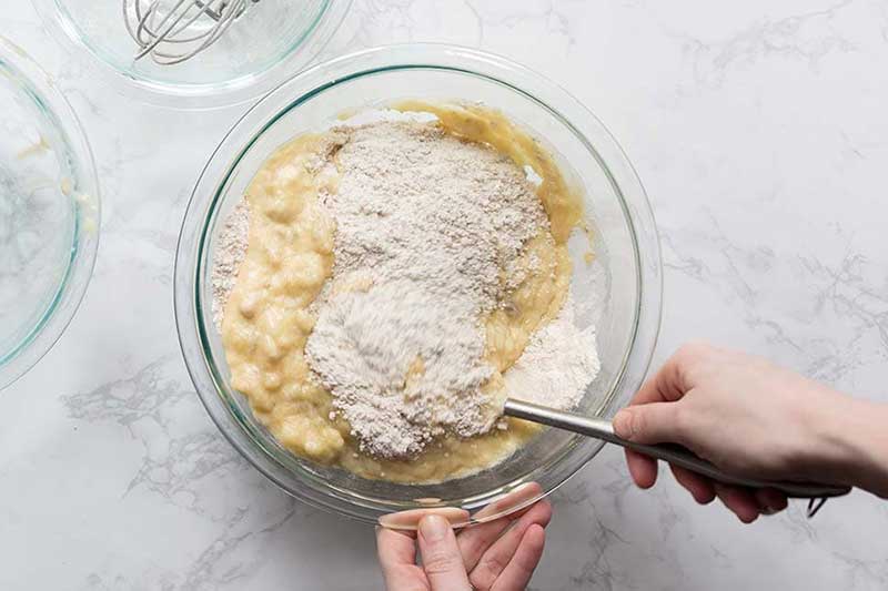 Stirring banana bread muffin recipe ingredients in a bowl.