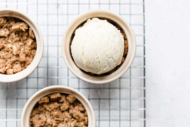 overhead photo of 3 apple crumble servings, 1 topped with ice cream