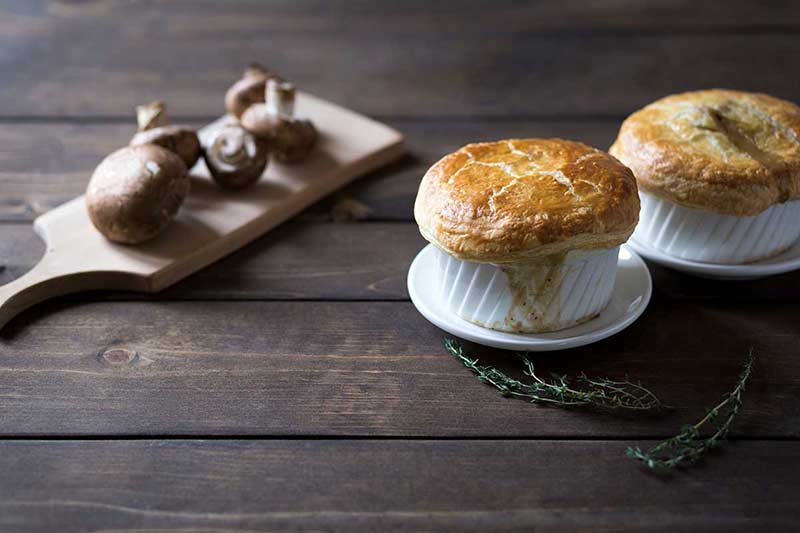 Two single serving pot pies next to mushrooms
