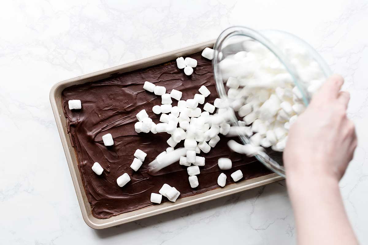 Pouring marshmallows over the chocolate pie layer.