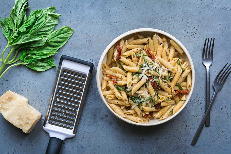 Sun-Dried Tomato Pesto Pasta surrounded by basil and parmesan