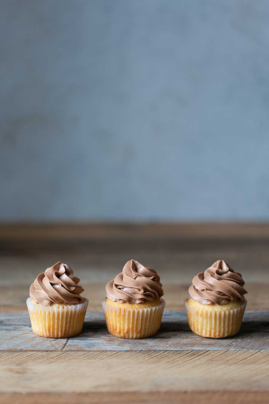 Three vanilla cupcakes with chocolate buttercream