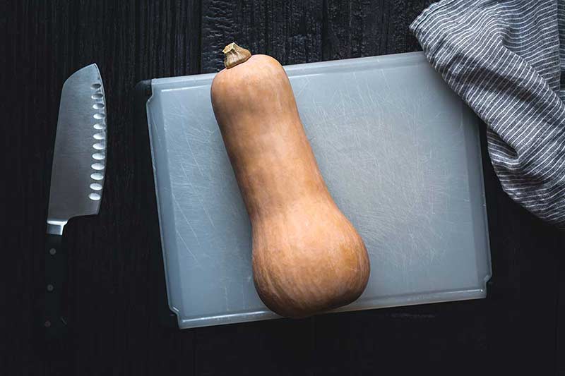butternut squash on a cutting board with a knife