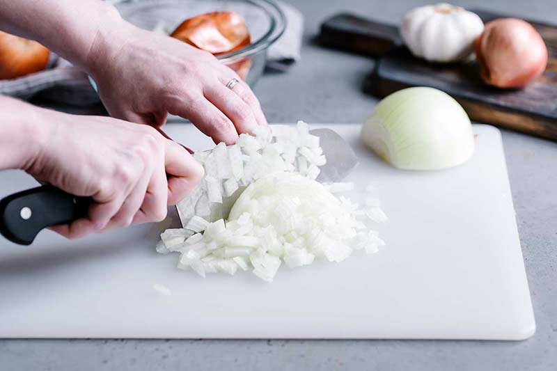 How to chop an onion tutorial demonstrating running the knife through chopped onion to further break up the pieces