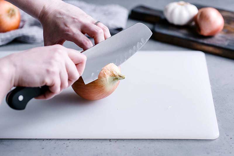 Slicing the stem end off a yellow onion