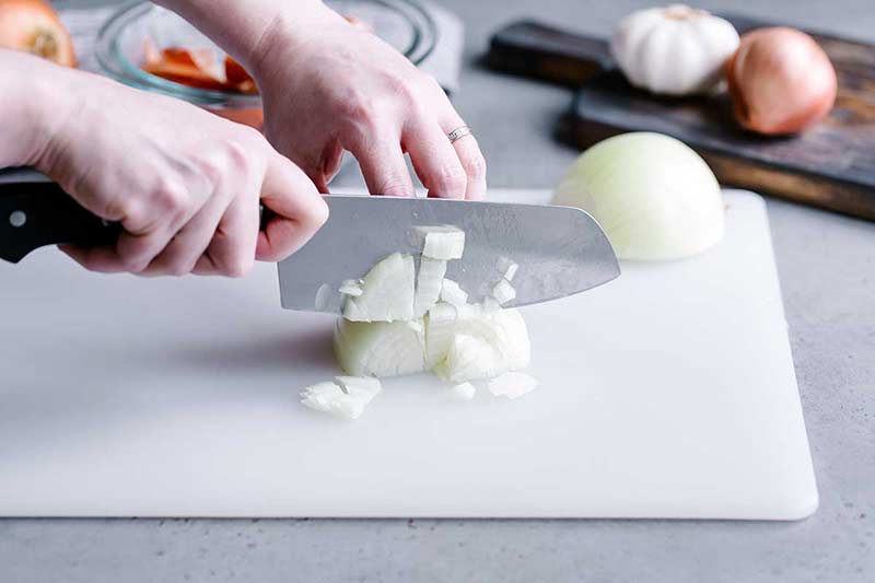 Using a chef's knife to create chopped onions from an onion half