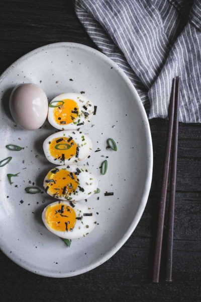 Ramen eggs on a plate with chopsticks