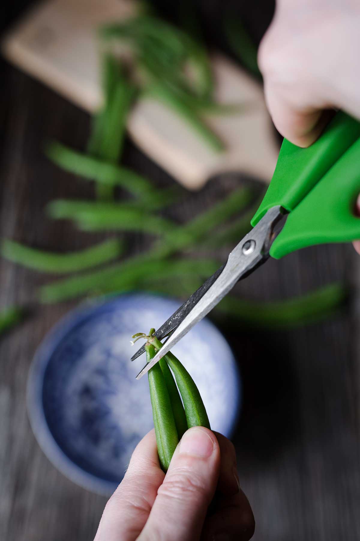 Trimming green beans with kitchen shears 