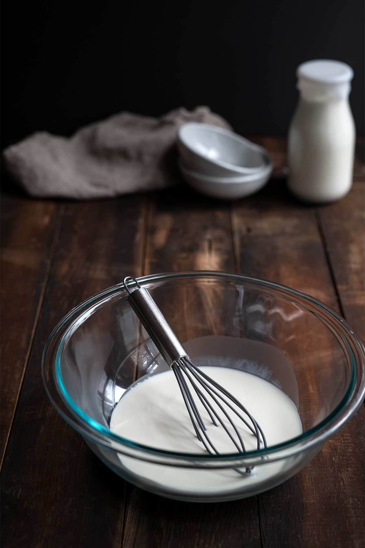 A bowl filled with cream and a whisk