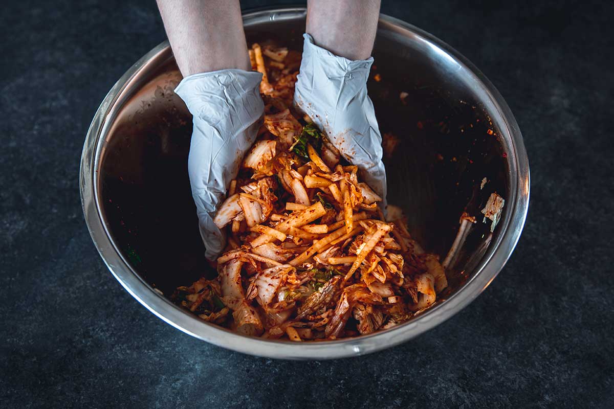 Mixing kimchi ingredients by hand in a bowl