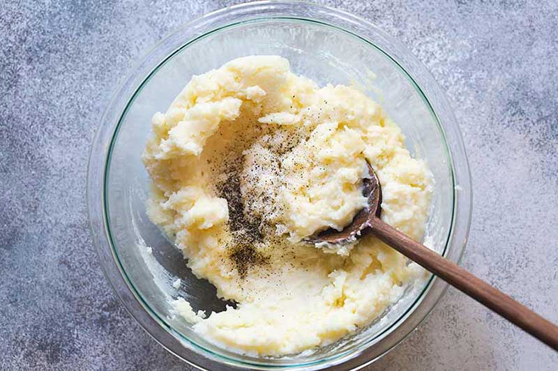 adding salt and pepper to mashed potatoes