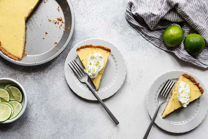 2 slices of key lime pie, the remaining pie in a dish, and limes