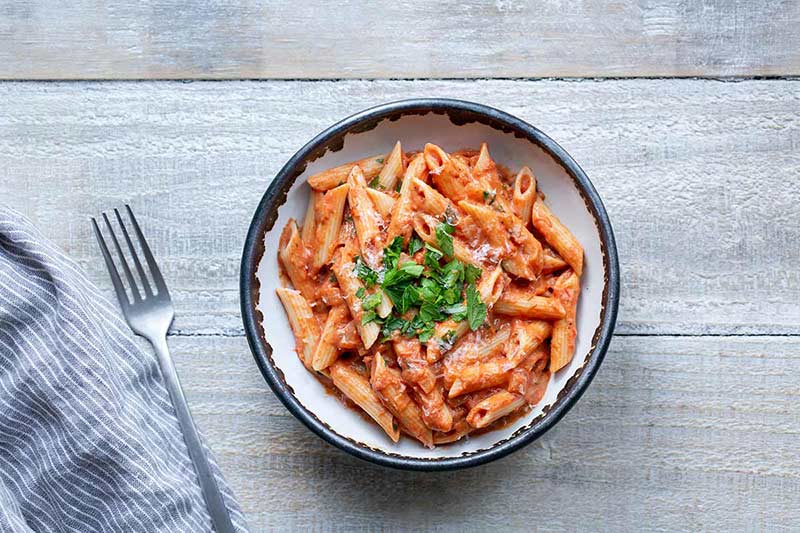 Penne with Vodka Sauce in a bowl with napkin and fork to the left