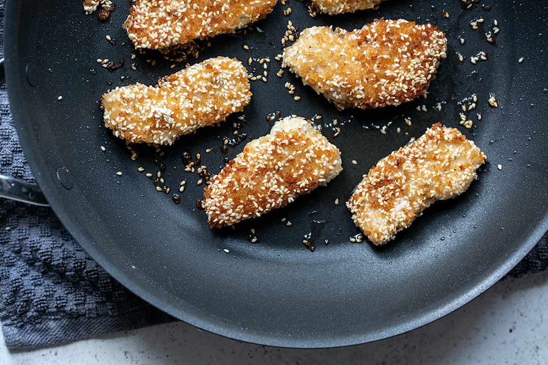 Crispy sesame chicken tenders in a nonstick skillet