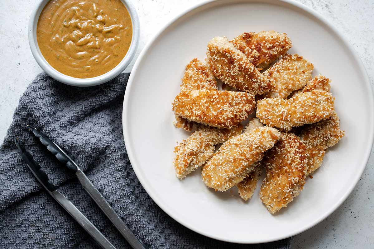 Crispy sesame chicken fingers recipe with spicy peanut sauce to the side