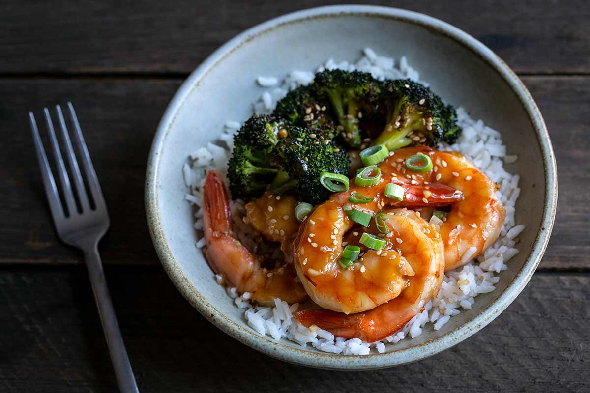 Honey garlic shrimp with fork on the left