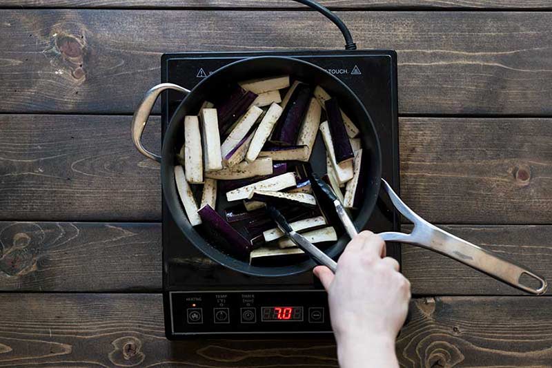 Chinese eggplant being sautéed in a skillet