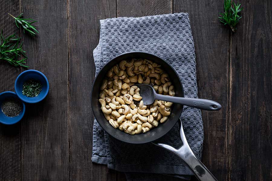 Raw cashews in a saucepan with olive oil