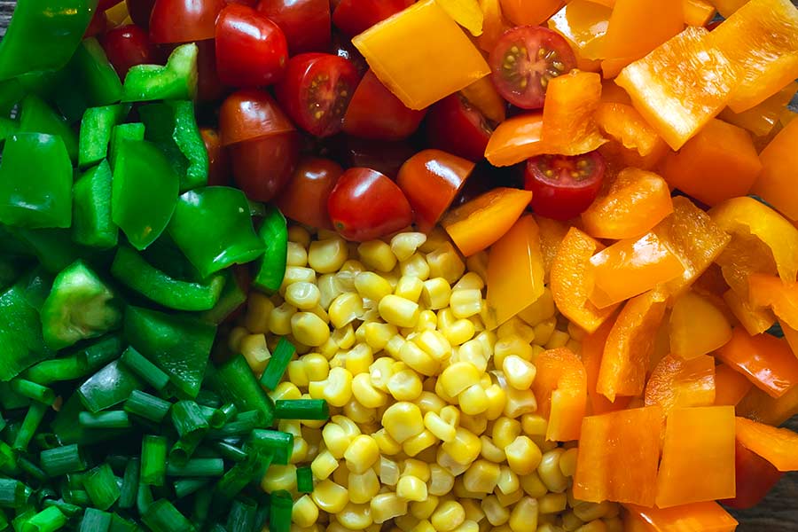 Closeup of ingredients, including bell peppers, tomatoes, and corn